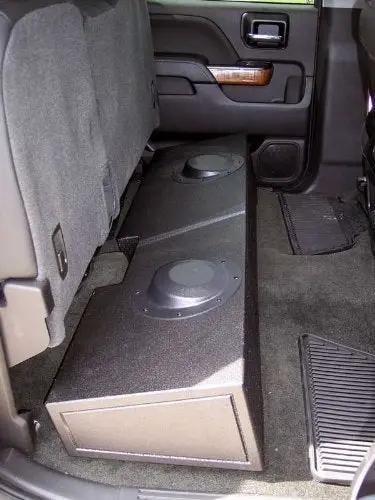 Enclosure installed beneath a raised rear bench seat, with two round raised sections and a flat end panel visible