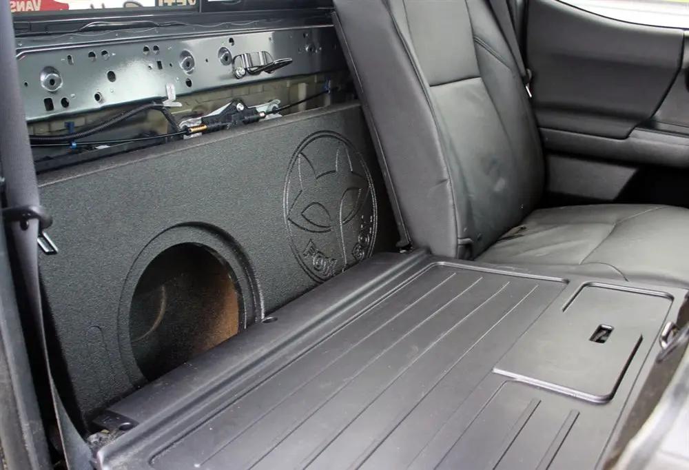 Fox Box enclosure positioned behind a folded-forward rear seat with an empty speaker opening visible