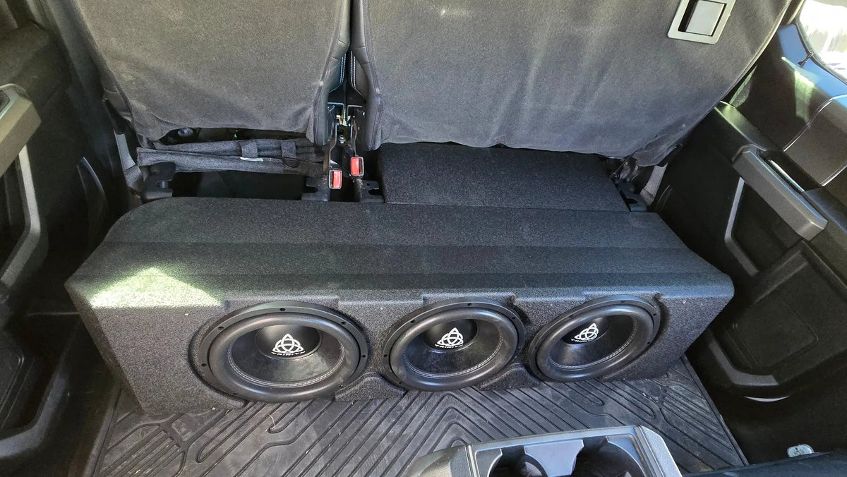 Installation example showing three subwoofers beneath raised rear seat cushions