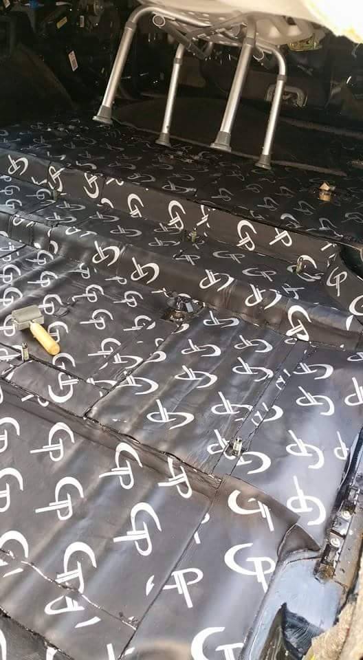 Close-up of GP-branded sound-deadening sheets fitted across a vehicle floor around mounting points