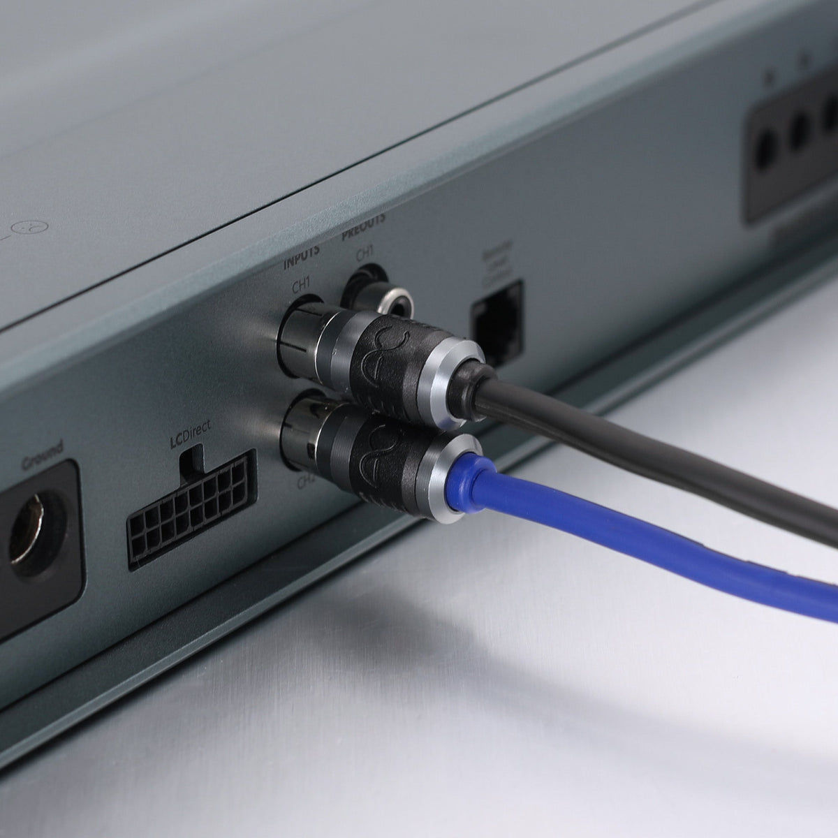 Close-up of audio or video input connectors on a silver electronic device, with a black cable and a blue cable plugged in.