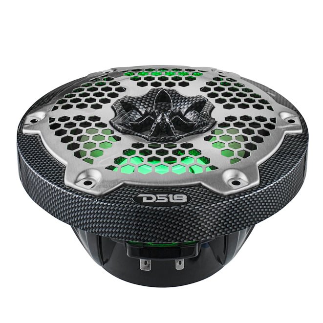 Low-angle view of a carbon-fiber-pattern DS18 speaker with silver honeycomb grille and green illumination