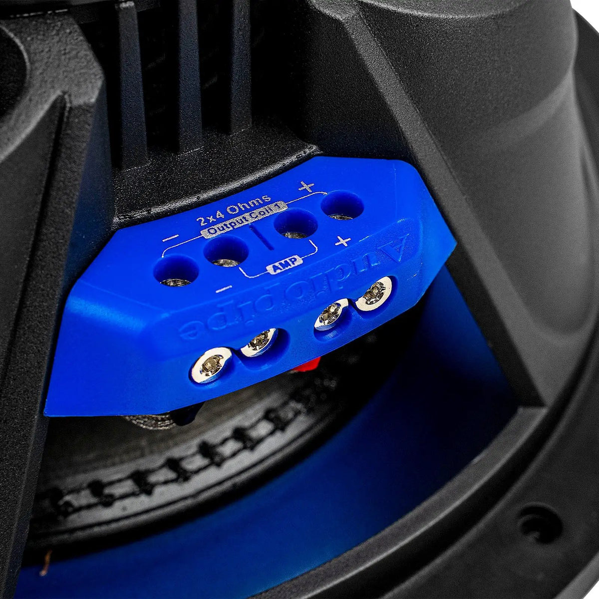Close-up of a blue Audiopipe subwoofer terminal block marked 2x4 ohms, with coil and amplifier connections