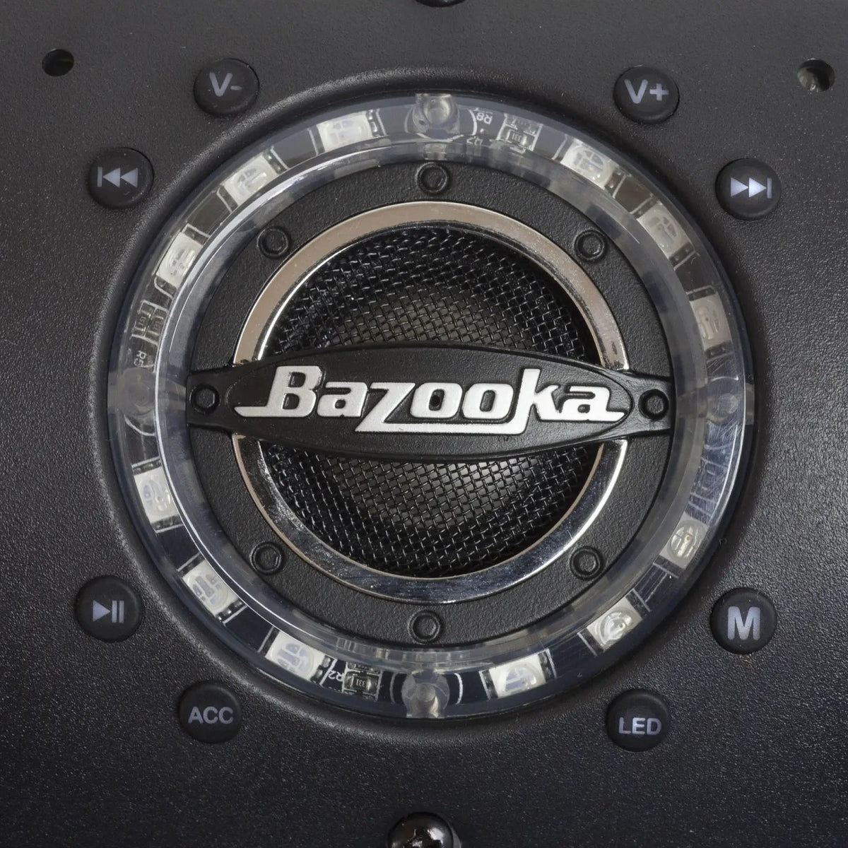 Close-up of a Bazooka soundbar speaker with an illuminated ring and volume, playback, mode, accessory and lighting buttons