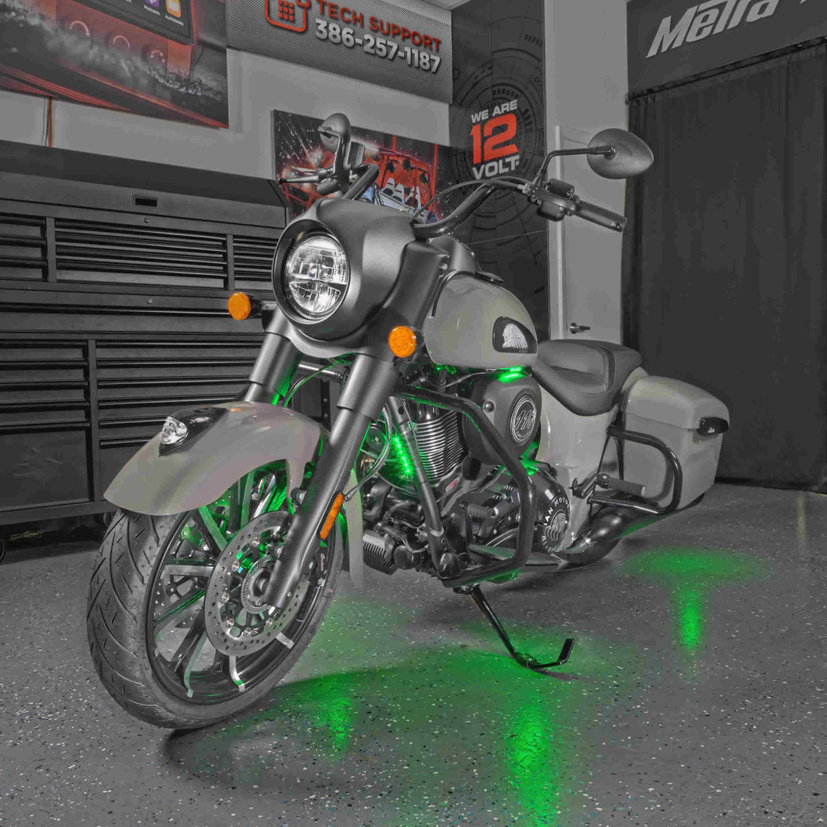 Motorcycle in a workshop with green accent lighting around the engine and beneath the frame