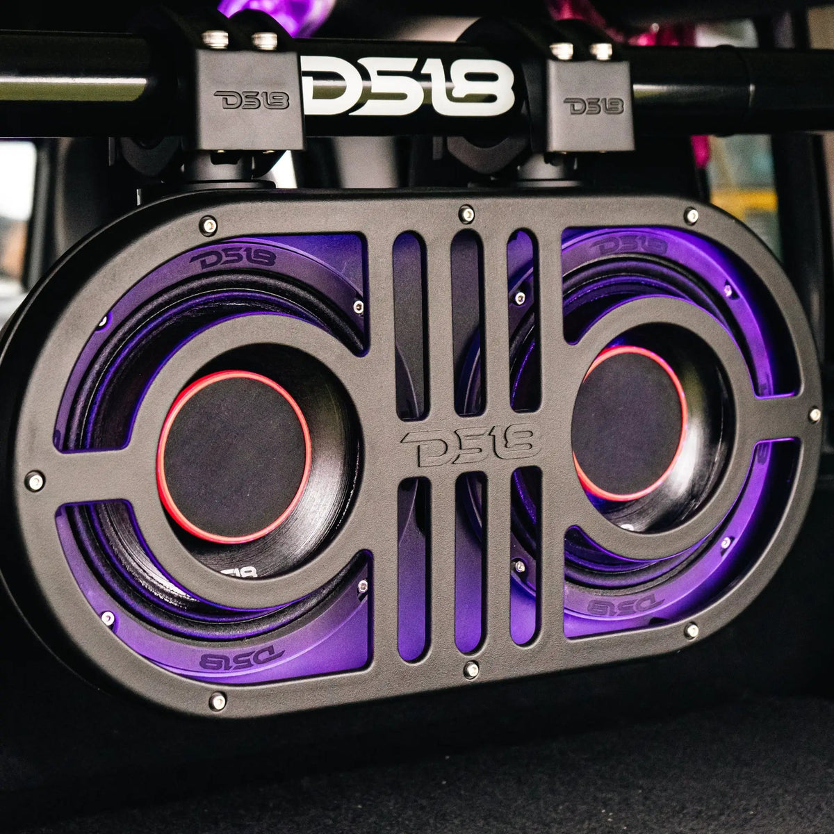 DS18 dual-speaker pod with purple lighting clamped to a horizontal bar