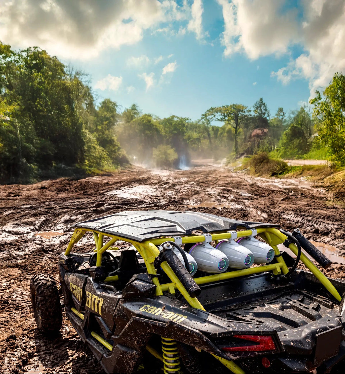 White tower speakers mounted on the rear roll bar of an off-road vehicle on a muddy trail