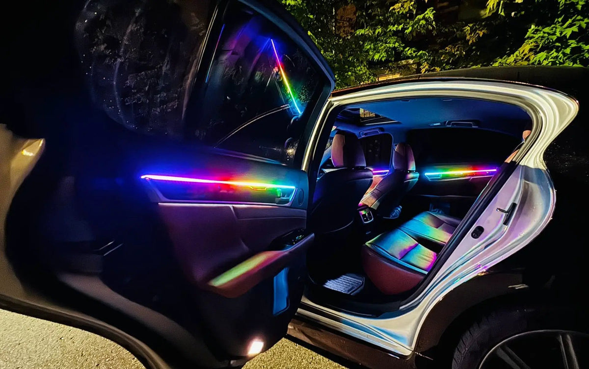 Car interior with rainbow-colored ambient lighting along the open doors and dashboard