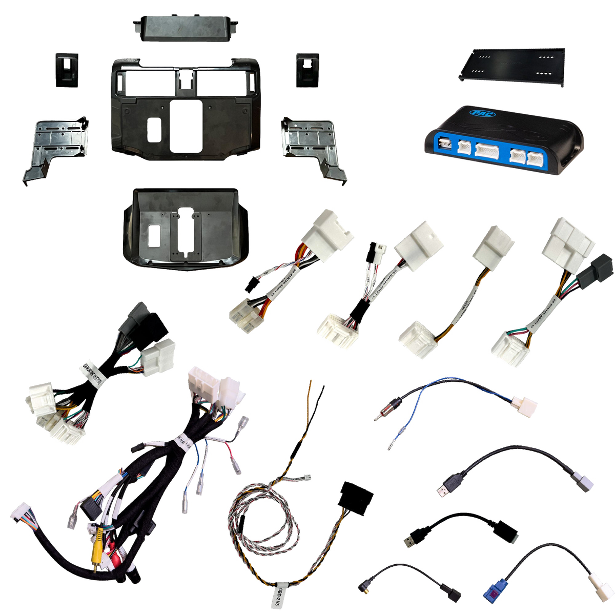 Radio installation components laid out with dashboard panels, brackets, an interface module, wiring harnesses and adapter leads