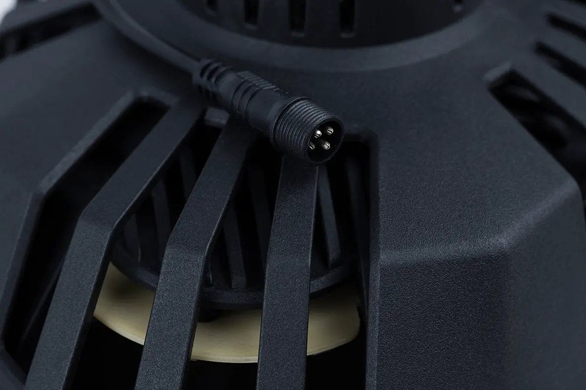 Close-up of a round four-pin connector beside a speaker basket