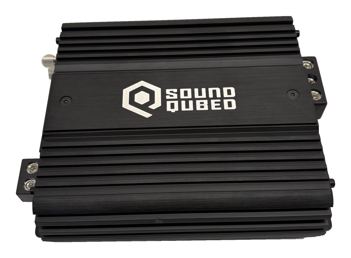 Angled view of a black SoundQubed amplifier with a finned housing and logo on top