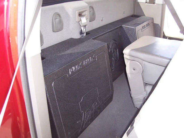 Black Fox Box enclosure positioned behind a seat, with its embossed logo and central recessed section visible