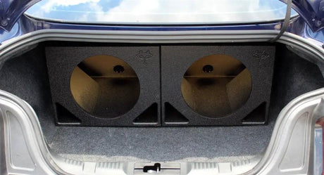 Two empty subwoofer enclosures positioned side by side in a car trunk