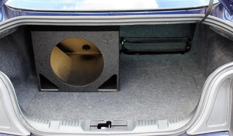 Single empty subwoofer enclosure positioned on one side of a car trunk