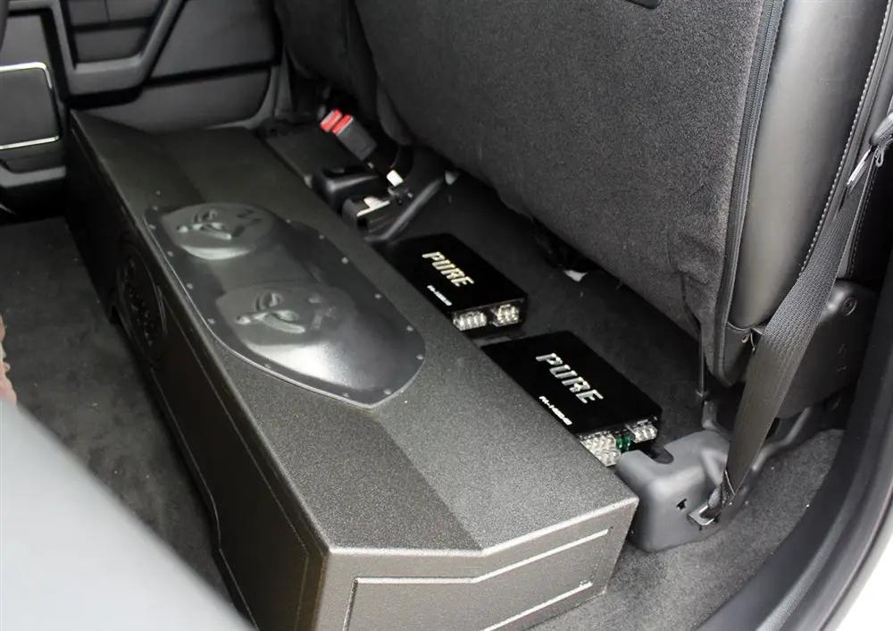 Installation example showing a subwoofer enclosure and two Pride amplifiers beneath raised rear seat cushions