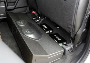 Installation example showing a subwoofer enclosure and two Pride amplifiers beneath raised rear seat cushions