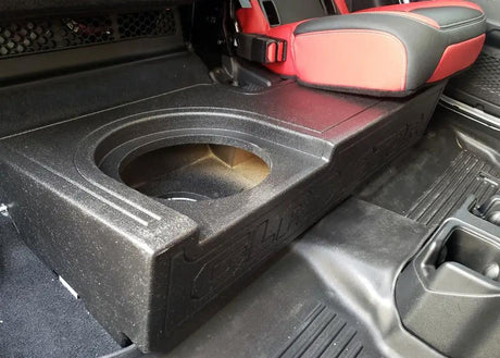 Close-up of the single speaker opening in a Fox Box Gladiator enclosure beneath a raised red-and-black rear seat