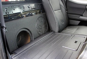Fox Box enclosure positioned behind a folded-forward rear seat with an empty speaker opening visible