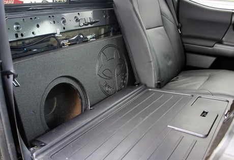 Fox Box enclosure positioned behind a folded-forward rear seat with an empty speaker opening visible