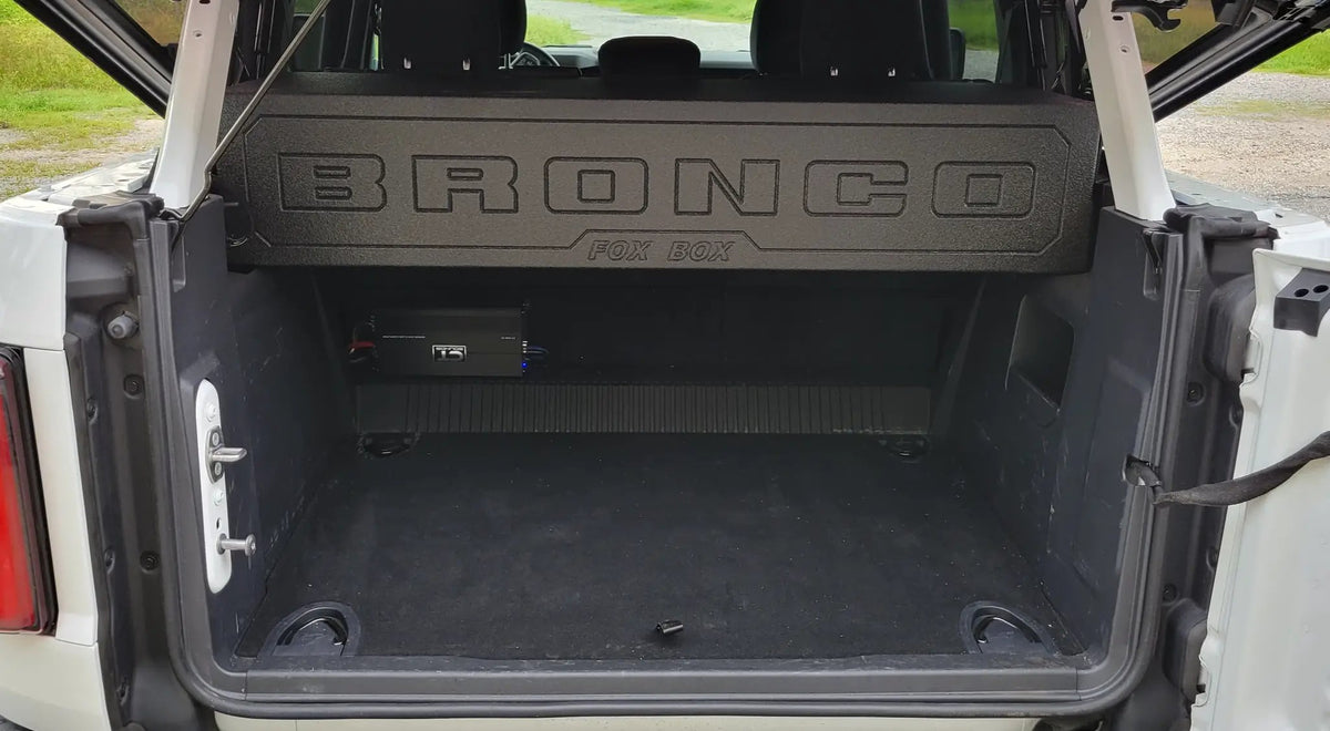 Ford Bronco cargo-area view showing the Fox Box enclosure behind the rear seats and an amplifier below it
