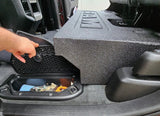 Subwoofer enclosure installation showing access to a floor-storage compartment with its mesh lid lifted