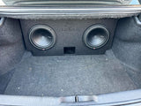 Fox Box enclosure with two installed subwoofers and a center port positioned in a carpeted trunk