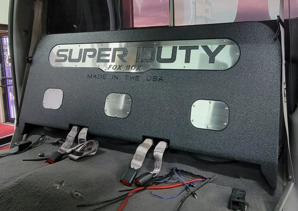 Black enclosure marked SUPER DUTY installed behind a truck's removed rear seat