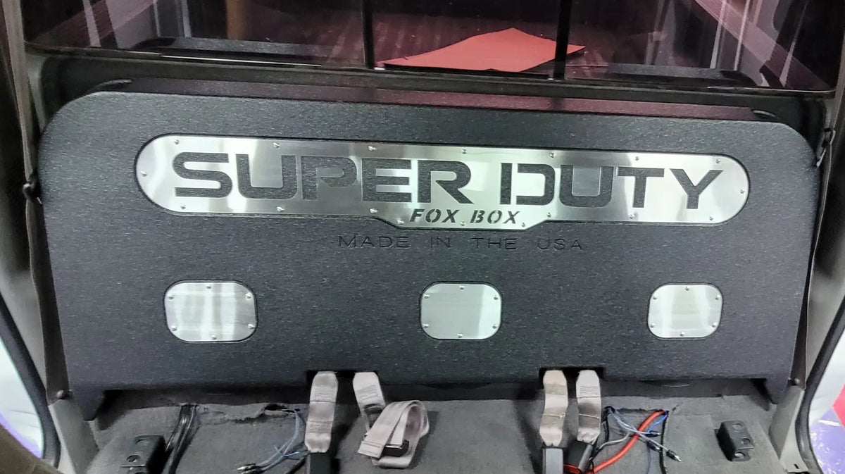FOX BOX enclosure installed behind a rear seat, with a silver SUPER DUTY panel and three access openings