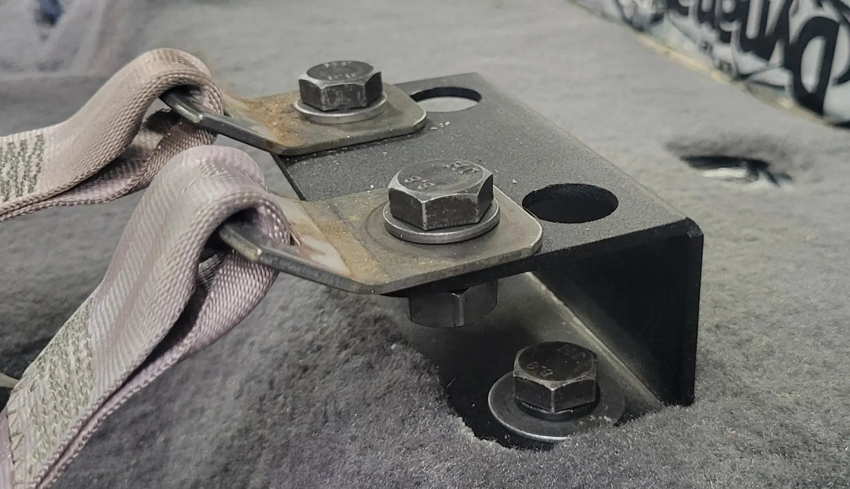 Close-up of installed seat-lift brackets and bolts securing the seat-belt anchors