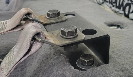 Close-up of installed seat-lift brackets and bolts securing the seat-belt anchors