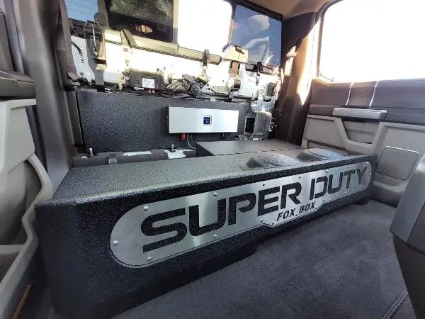 Fox Box enclosure installed behind a raised truck rear seat, with a silver SUPER DUTY front panel