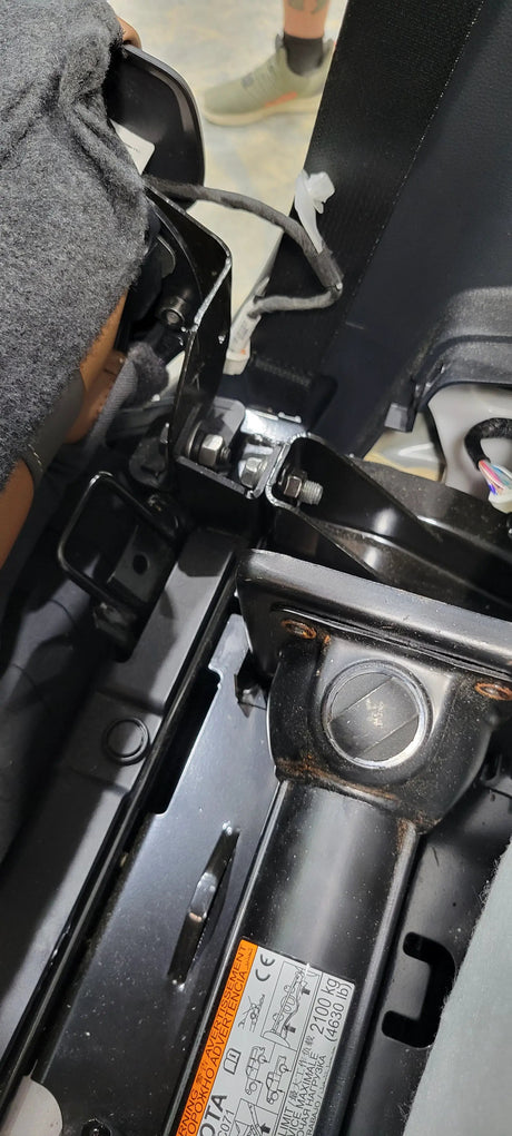 Close-up of seat mounting hardware and a bolted black bracket beside the seat frame