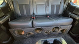 Black enclosure with six empty speaker openings installed beneath a truck rear bench seat