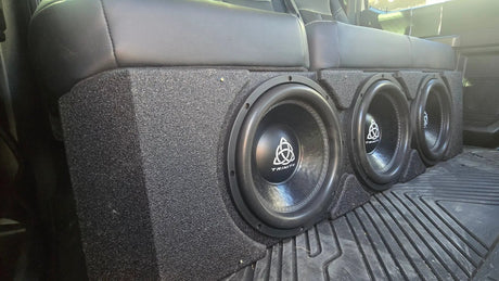 Installation example showing three Trinity subwoofers in an enclosure beneath a rear bench seat