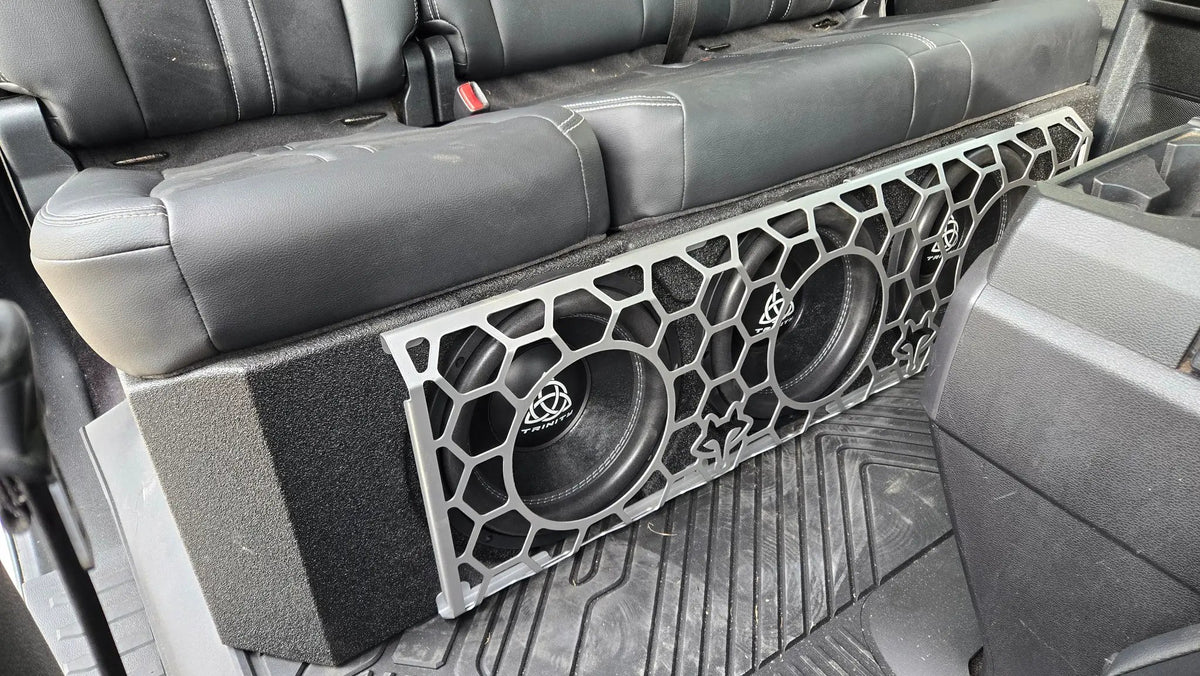 Fox Box Ford triple-subwoofer installation under the rear seat, with a honeycomb-pattern grille covering the speaker cones