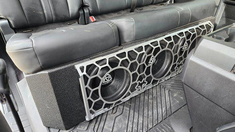 Fox Box Ford triple-subwoofer installation under the rear seat, with a honeycomb-pattern grille covering the speaker cones