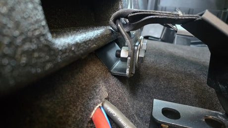 Close-up of the Fox Box Ford Super Duty enclosure mounting bracket and adjacent seat-belt hardware