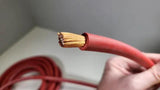 Close-up of a hand holding red cable with the stranded conductor exposed