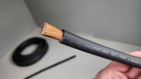 Hand holding black TRU SPEC cable with the stranded conductor exposed