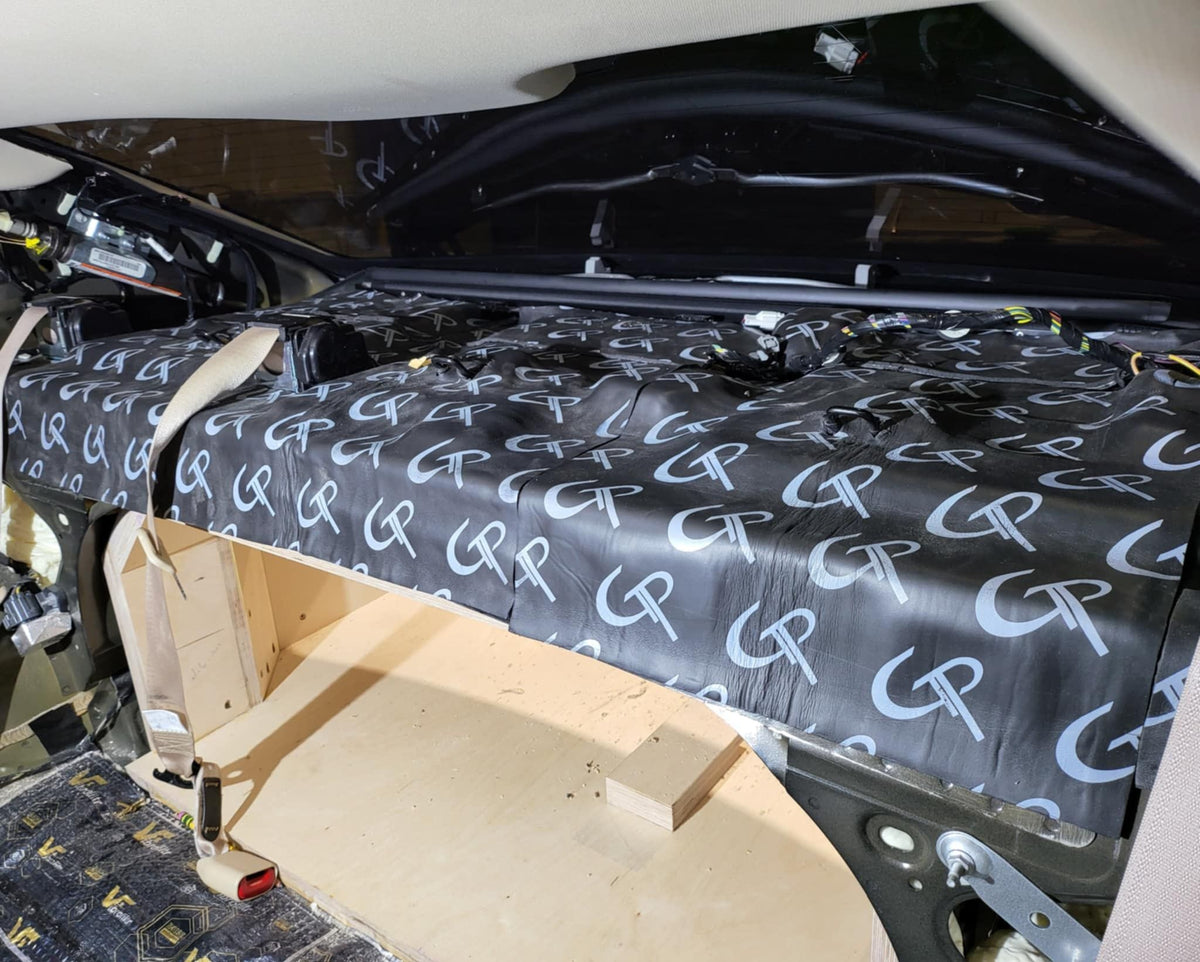 GP-branded sound-deadening sheets fitted across a vehicle interior panel above a wood support frame