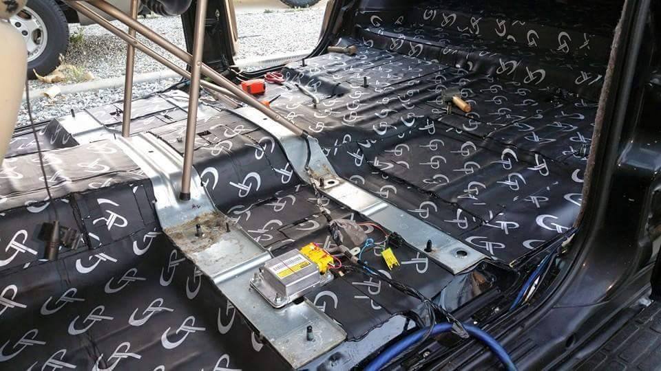 GP sound-deadening sheets fitted around the center tunnel and floor of a stripped vehicle cabin