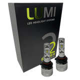 Two Lumi Stage 2 9005 LED Headlight Bulbs with advanced CSP chips are displayed in front of a black box labeled â€œLUMI LED Headlight Systems 2 Stage II Headlight Kitâ€ on a plain background. Each bulb delivers an impressive 6000 lumens, ensuring bright and efficient illumination.