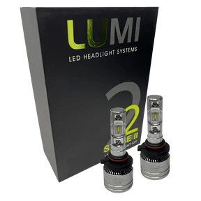 Two Lumi Stage 2 9005 LED Headlight Bulbs with advanced CSP chips are displayed in front of a black box labeled â€œLUMI LED Headlight Systems 2 Stage II Headlight Kitâ€ on a plain background. Each bulb delivers an impressive 6000 lumens, ensuring bright and efficient illumination.