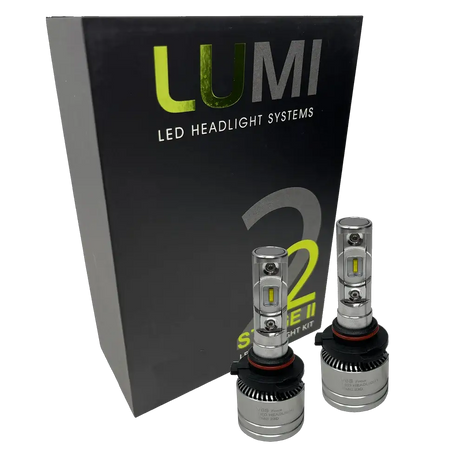 Two Lumi Stage 2 9005 LED Headlight Bulbs with advanced CSP chips are displayed in front of a black box labeled â€œLUMI LED Headlight Systems 2 Stage II Headlight Kitâ€ on a plain background. Each bulb delivers an impressive 6000 lumens, ensuring bright and efficient illumination.