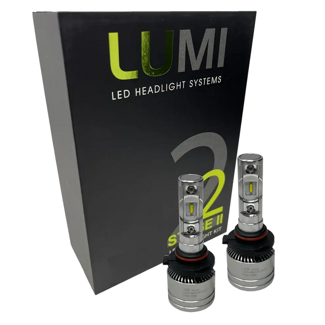 Two Lumi Stage 2 9005 LED Headlight Bulbs with advanced CSP chips are displayed in front of a black box labeled â€œLUMI LED Headlight Systems 2 Stage II Headlight Kitâ€ on a plain background. Each bulb delivers an impressive 6000 lumens, ensuring bright and efficient illumination.
