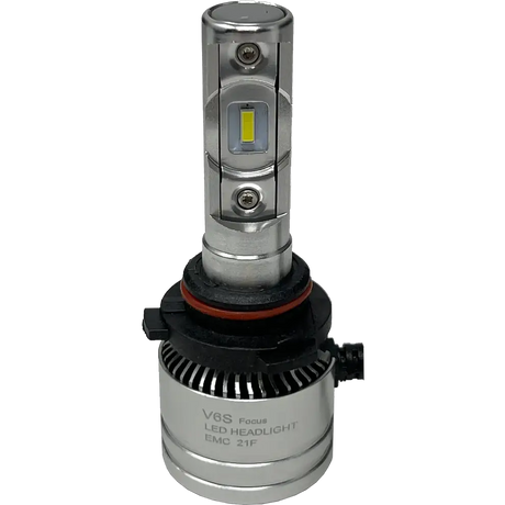Introducing the LUMI Stage 2 9007 LED Headlight Bulbs by Lumi: Featuring a silver design with integrated cooling fins, a black and red gasket at the base, and visible CSP chips on the front for improved brightness. The bulbs include a black connector attached at the bottom, and â€œV6S Focus LED HEADLIGHT EMC 21Fâ€ printed on the base. These Lumi headlights emit a crisp 6000K white light, delivering superior visibility for nighttime driving.