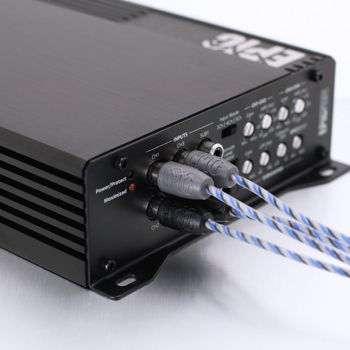 Close-up of the rear panel of a black audio power amplifier, showing input jacks, control knobs, and blue-and-white braided cables plugged in on a white background.