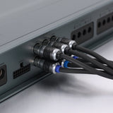Close-up of audio or video cables plugged into the rear panel of a gray electronic device, showing black cables with silver connectors and blue ring accents.