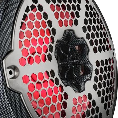 Close-up of a speaker's silver honeycomb grille, central tweeter and carbon-fiber-patterned trim with red illumination.