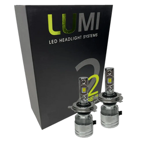 Two LUMI Stage 2 H4 LED Headlight Bulbs with advanced CSP chips are displayed in front of a black Lumi LED Headlight Systems box featuring green and white text, highlighting their brilliant 6000K illumination.